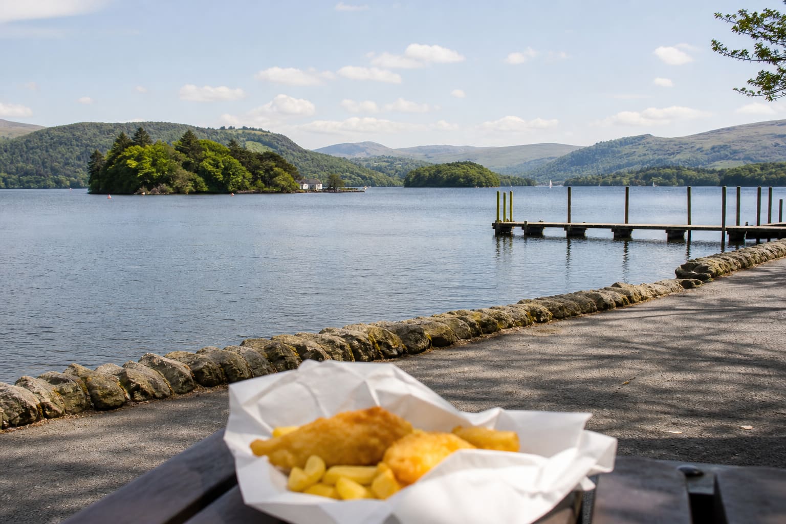 Lake Windermere from the Bowness shoreline, with a parcel of fish and chips on a bench